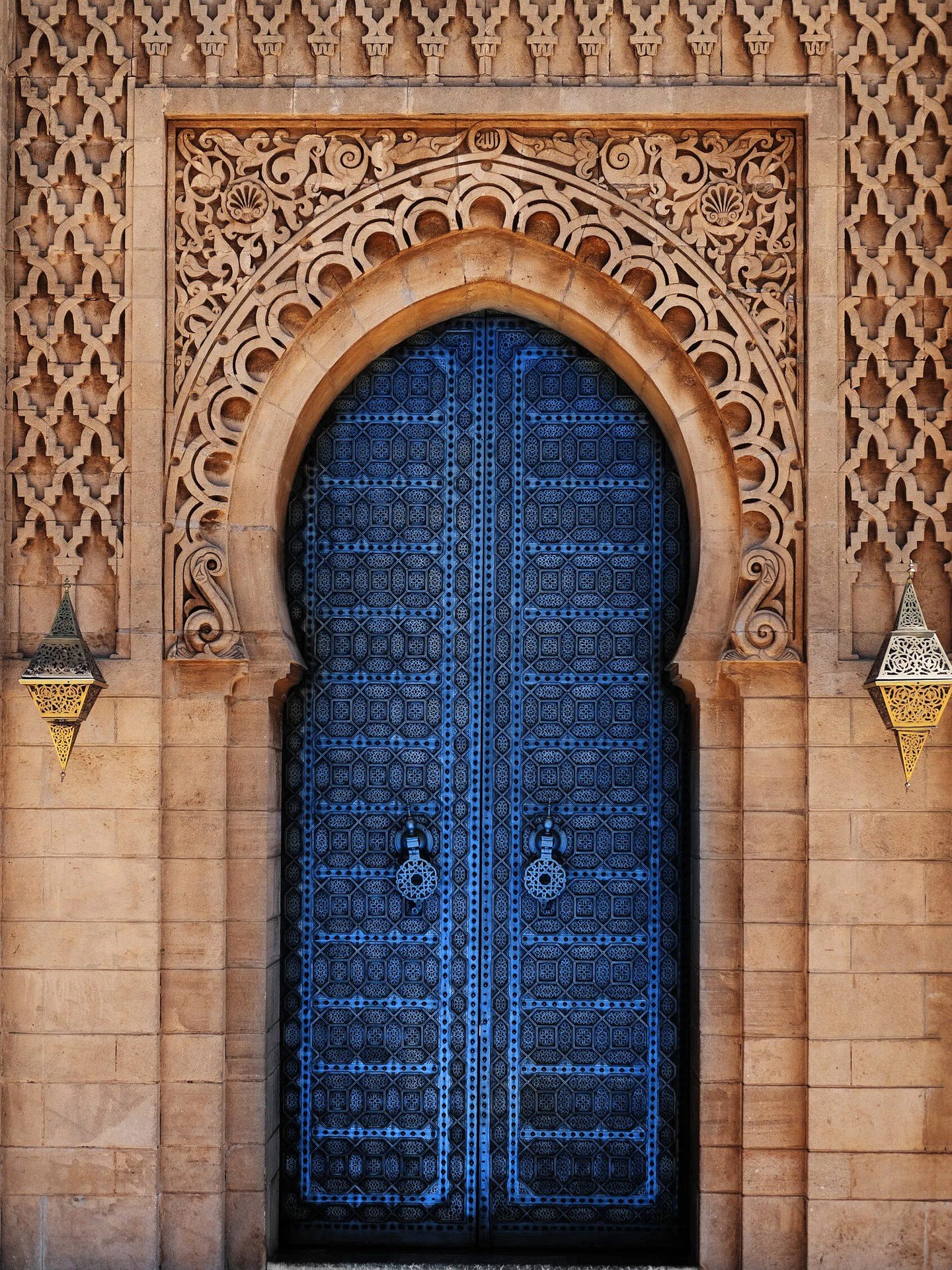 An ornate blue Moroccan arched door set in a carved stone facade